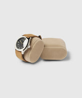 A TAWBURY wristwatch with a black dial and silver casing is displayed on a beige Bayswater Watch Box Pillow - 50mm - X-Small, inside the box with an additional empty pillow.