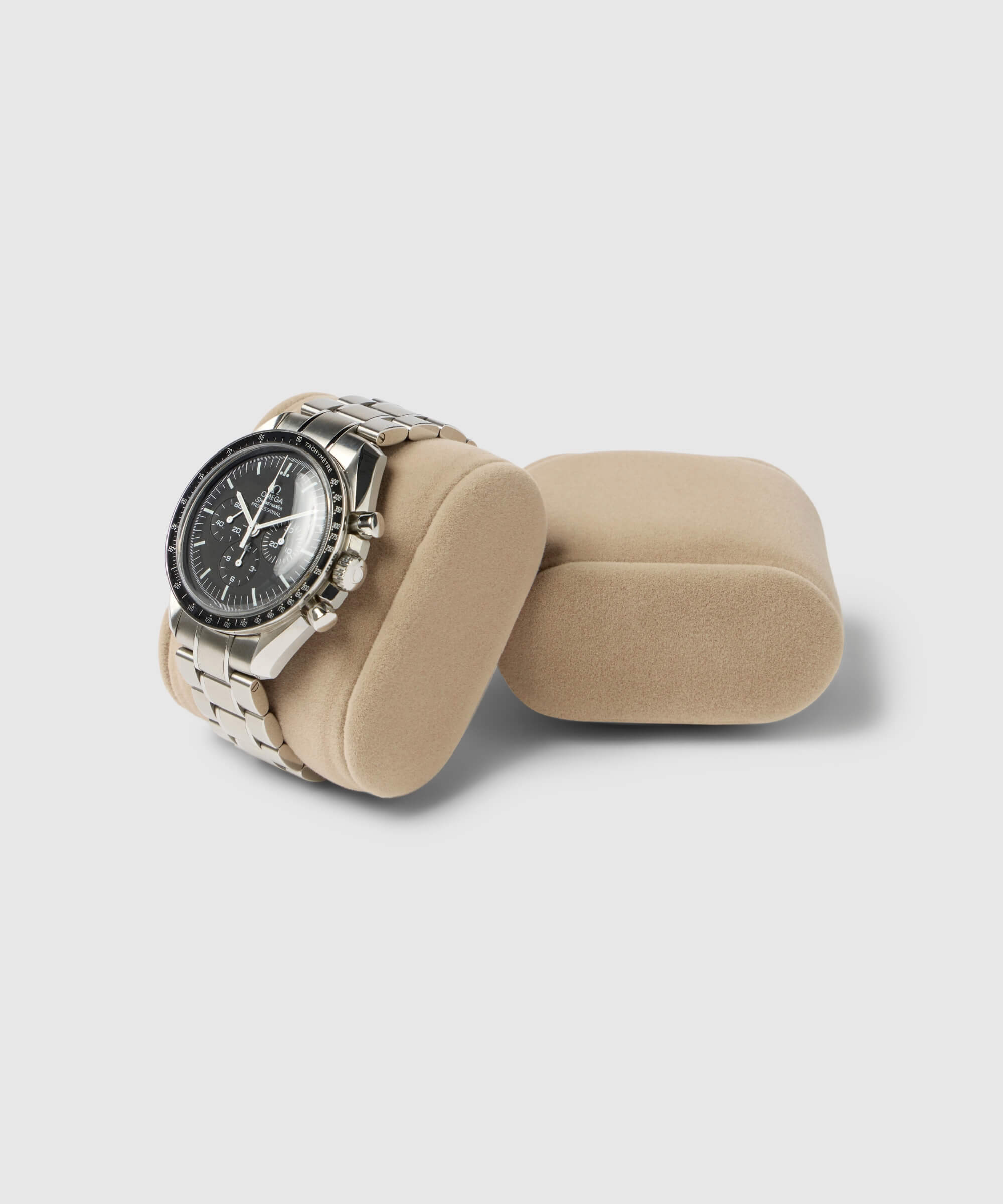 A Bayswater Watch Box Pillow (55mm, Small) in beige by TAWBURY displays a silver watch with a black dial elegantly on its soft velveteen fabric against a simple light background.