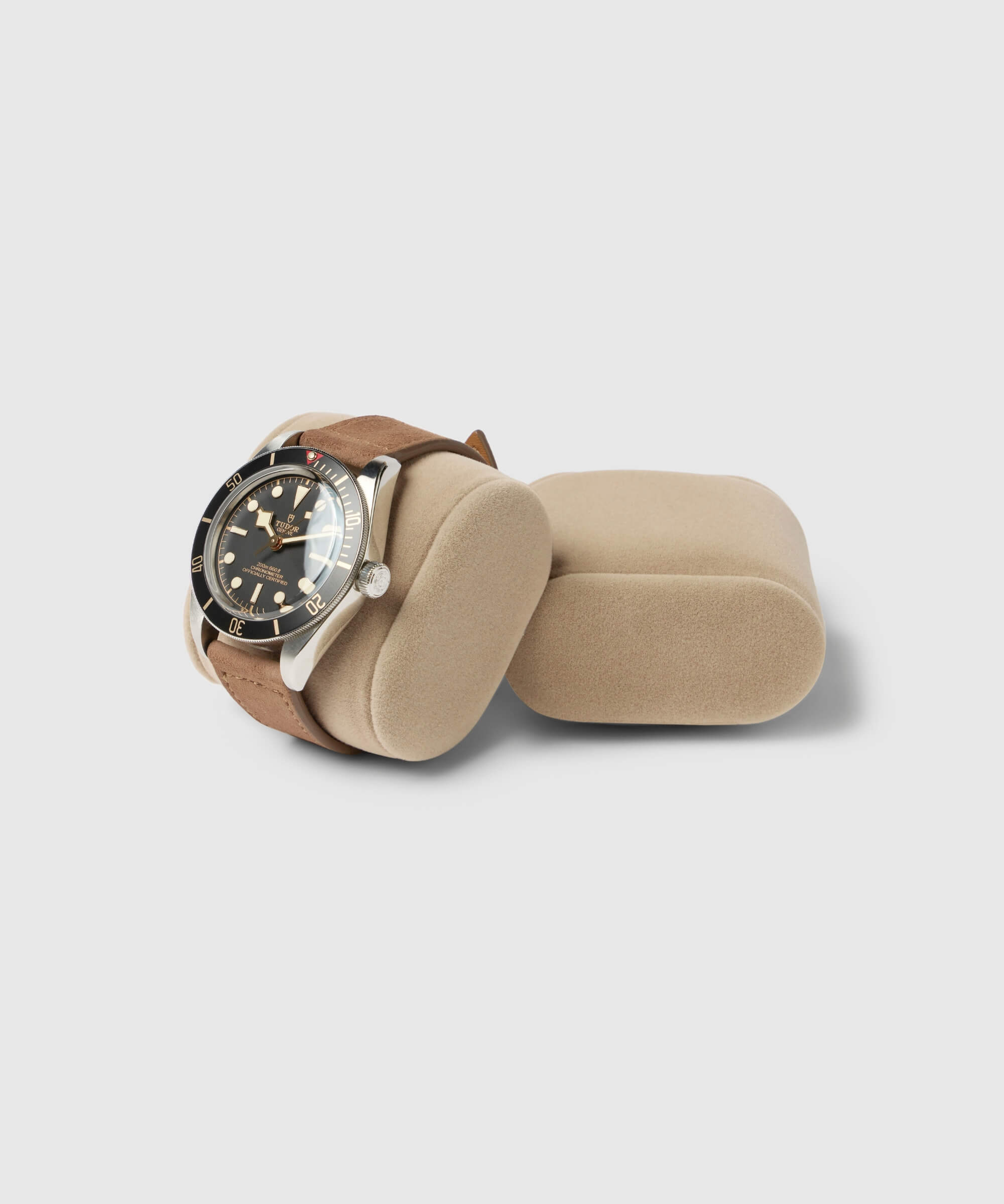 A wristwatch with a brown leather strap sits elegantly on a Bayswater Watch Box Pillow - Beige 55mm X-Small by TAWBURY.