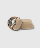 A wristwatch with a brown leather strap sits elegantly on a Bayswater Watch Box Pillow - Beige 55mm X-Small by TAWBURY.