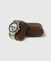A Bayswater Watch Box Pillow in Brown/Grey by TAWBURY elegantly displays a silver wristwatch with a white and black dial, exemplifying sophistication for those seeking customisable 50mm watch storage solutions.