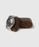 A stainless steel watch with a black dial and link bracelet sits elegantly on a Bayswater Watch Box Pillow by TAWBURY, perfect for any wrist size. Effortlessly complementing any collection, the brown cushion stand is ideal for display in one of the Bayswater 8 Slot Watch Boxes.