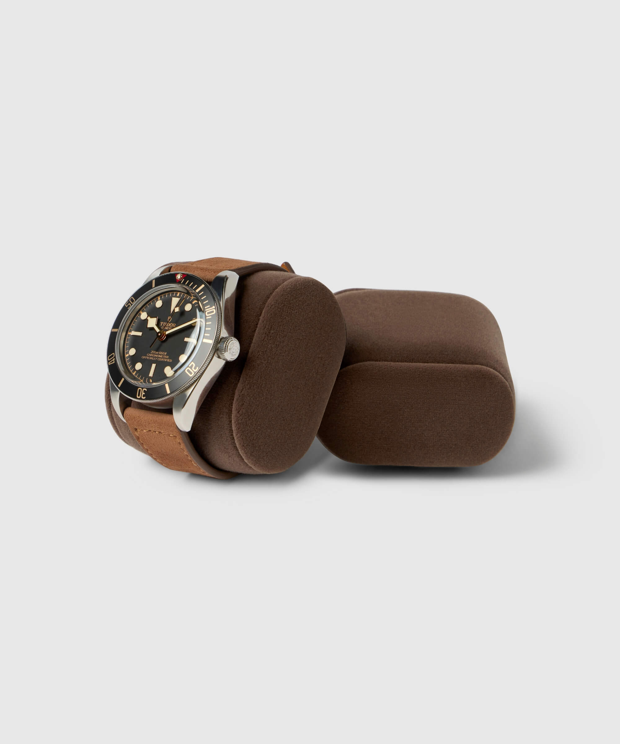 A stainless steel watch with a black dial and brown leather strap is elegantly displayed on a brown cushion beside an empty one, perfectly embodying the luxury of TAWBURY's Bayswater Watch Box Pillows in Brown/Grey, X-Small (55mm).