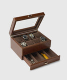 The TAWBURY Bayswater 8 Slot Watch Box with Storage - Brown is designed with vegan leather and prominently displays up to eight watches when the lid is open. Additionally, a drawer beneath provides space for extra strap storage, catering to watch enthusiasts.