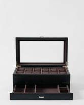 The TAWBURY Bayswater 12 Slot Watch Box with Storage in Black/Charcoal features a transparent lid, twelve padded watch compartments, and extra open sections in a pull-out drawer below.
