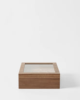 The TAWBURY Grove 12 Slot Wooden Watch Box in light walnut with a glass lid is shown against a white background—perfect for elegant watch storage.