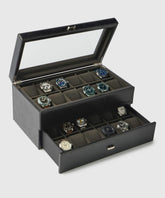The Bayswater 24 Slot Watch Box with Drawer by TAWBURY is made from vegan leather and features a glass exhibition window, elegantly showcasing watches in two-tiered compartments.