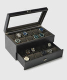 The Bayswater 24 Slot Watch Box with Drawer by TAWBURY is made from vegan leather and features a glass exhibition window, elegantly showcasing watches in two-tiered compartments.