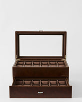 The TAWBURY Bayswater 24 Slot Watch Box with Drawer in brown features a glass lid, an upper compartment for 12 watches, and a lower pull-out drawer with extra slots to organize your collection.