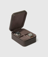 The TAWBURY Fraser 4 Watch Travel Case in brown, featuring a leather exterior and zipper closure, is open to display two watches in individual compartments against a plain background.