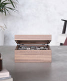 A TAWBURY Grove 6 Slot Wooden Watch Box, crafted from walnut wood and featuring a glass lid, reveals neatly arranged watches inside, placed on a table in a minimalistic room.