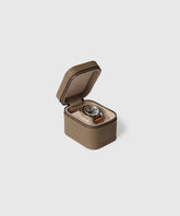 The TAWBURY Fraser 1 Watch Travel Case - Taupe (Coming Soon) is shown open, displaying a wristwatch inside its light, cushioned interior. The brown textured leather case features a zipper for secure storage.