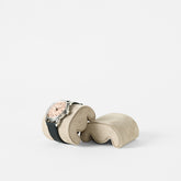 A wristwatch with a light face and black strap rests on a TAWBURY Fraser Watch Pillow (X-Small, Beige), displayed against a plain white background.