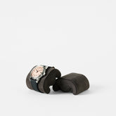 A wristwatch with a black strap and light dial rests on a TAWBURY Fraser Watch Pillow (X-Small, Anthracite), displayed against a plain white background.