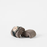 A wristwatch with a black strap and light face rests on a TAWBURY Fraser Watch Pillow, X-Small, in brown, against a plain white background.