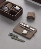 The TAWBURY Fraser 4 Watch Travel Case in brown displays two elegant timepieces and includes a green strap, a metal strap, and necessary tools for versatile styling and superb watch storage.