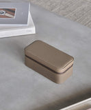 A Fraser 3 Watch Travel Case - Taupe by TAWBURY on a table next to a book providing protection for watches.