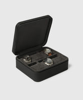 The open Fraser 6 Watch Case - Black by TAWBURY displays three uniquely designed wristwatches in its four compartments against a light gray background.