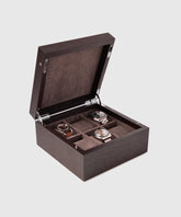 The TAWBURY Grove 6 Slot Wooden Watch Box, crafted from kassod wood with a solid lid, opens to reveal four compartments. Three of the compartments showcase watches, each boasting a distinct design and face. The interior is elegantly lined with dark fabric. This sophisticated piece is perfect for displaying timepieces in high-quality wooden watch cases like the Grove 6 Watch Box.