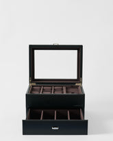 The TAWBURY Bayswater 6 Watch Jewelry Box in Black/Charcoal features vegan leather, a glass lid, top compartments for watches or jewelry, and an open lower drawer with extra divided sections, shown against a white background.