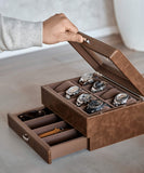 Hand opening the TAWBURY Bayswater 8 Slot Watch Box with Storage - Brown, displaying six watches on a scratch-free interior, and revealing a drawer below containing watch straps and accessories.