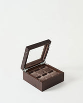 The TAWBURY Grove 6 Slot Wooden Watch Box features a dark walnut finish, glass lid, and six cushioned compartments lined with brown fabric for elegant watch storage.