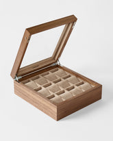 Showcasing the TAWBURY Grove 12 Slot Wooden Watch Box in light walnut with a glass lid, this elegant organizer features 12 beige cushioned compartments for watches and jewelry, photographed against a plain white background.