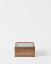 The TAWBURY Grove 6 Slot Wooden Watch Box in light walnut wood, featuring a glass lid, is displayed against a plain white background for an elegant presentation.