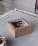 The TAWBURY Grove 6 Slot Wooden Watch Box in walnut wood with a glass lid beautifully displays several wristwatches inside, sitting on a gray table.