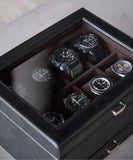 The TAWBURY Bayswater 8 Slot Watch Box in black charcoal PU leather with a transparent lid elegantly stores watches in eight compartments, making it essential for collectors.