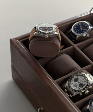 A Fraser 2 Watch Travel Case with Storage - Brown by TAWBURY, a small brown leather box with a top-grain leather exterior, sitting on a table.