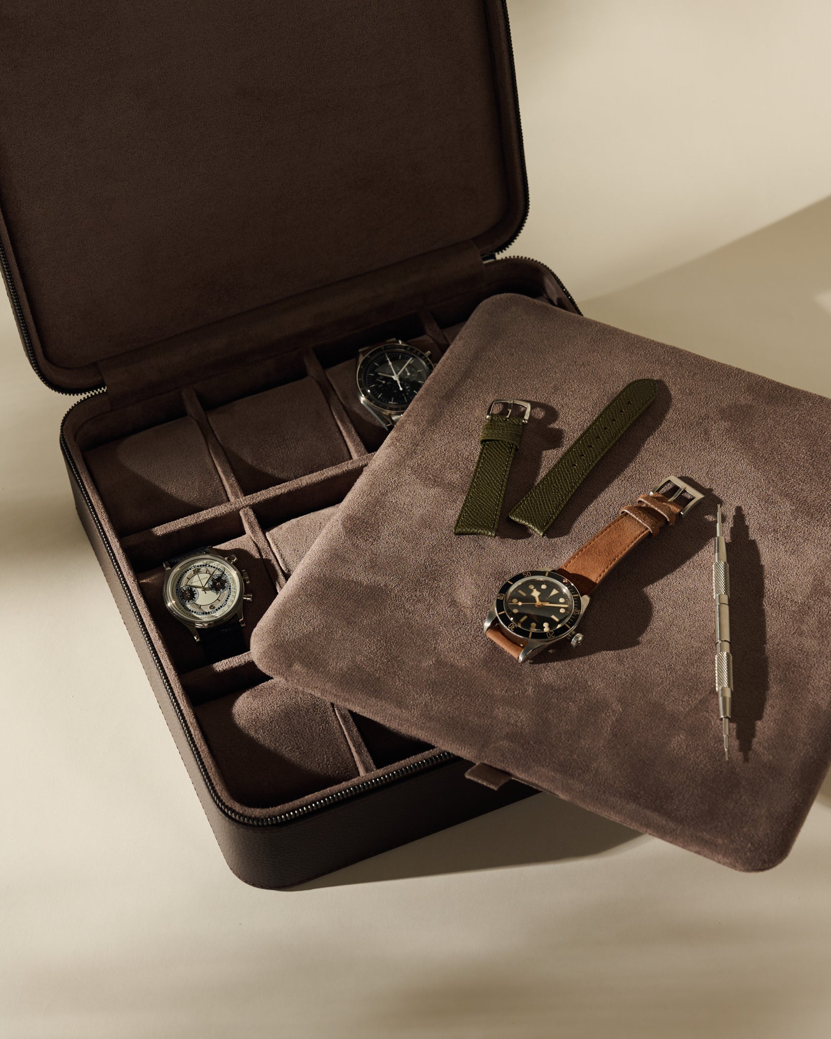 An espresso brown TAWBURY Fraser 12 Watch Case holding two watches, with an additional watch, two spare straps, and a spring bar tool on the interior tray.