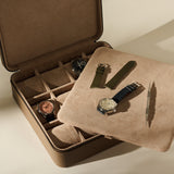An open TAWBURY Fraser 12 Watch Case in Truffle Taupe containing two wristwatches, with a tray holding an additional watch, two watch straps, and a spring bar tool.