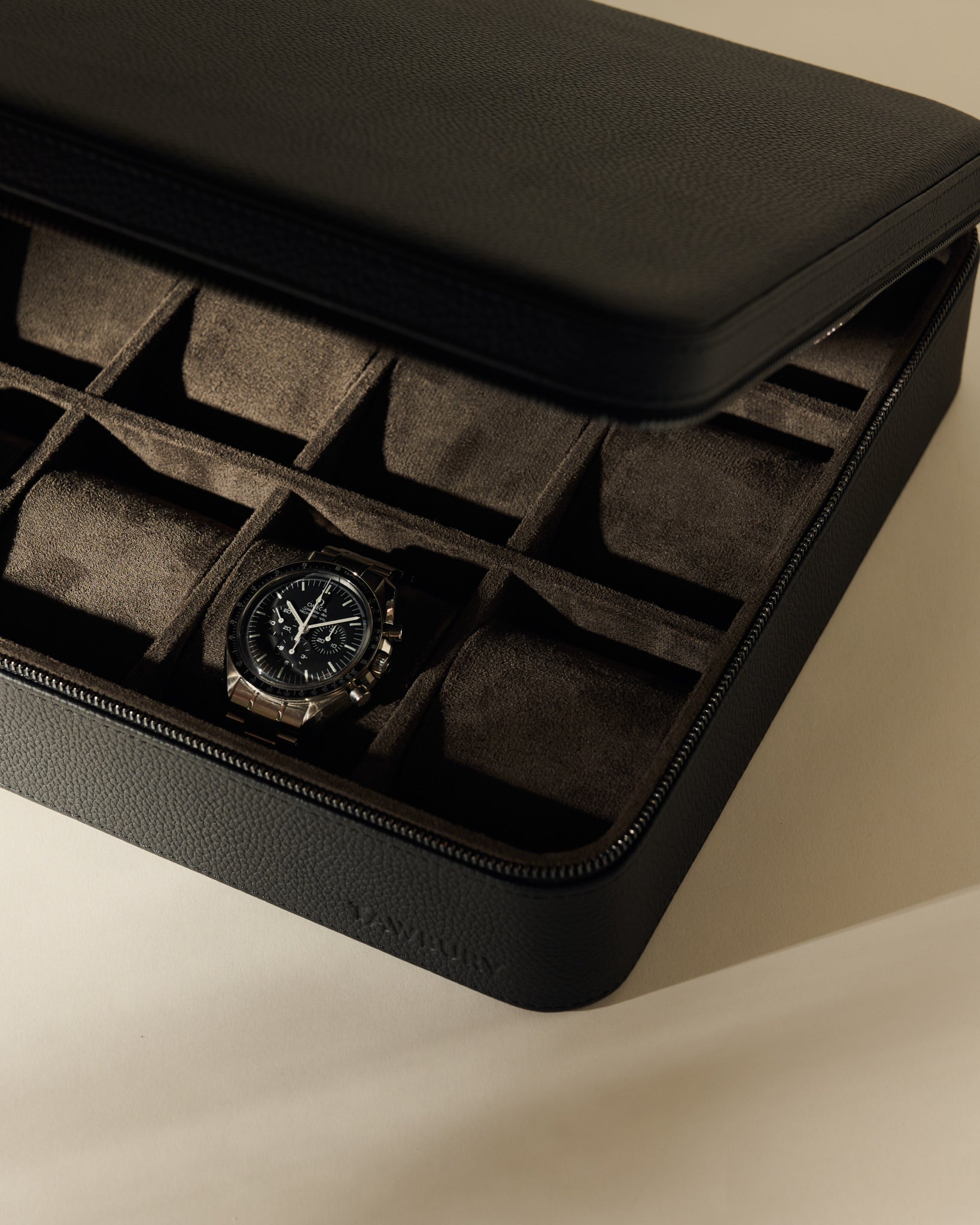 An open TAWBURY Fraser 12 Watch Case - Midnight Black containing a single chronograph wristwatch in a twelve-compartment tray.