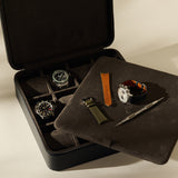 Open TAWBURY Fraser 12 Watch Case - Midnight Black with slots containing two watches, two spare watch straps, and a spring bar tool for organized watch storage.