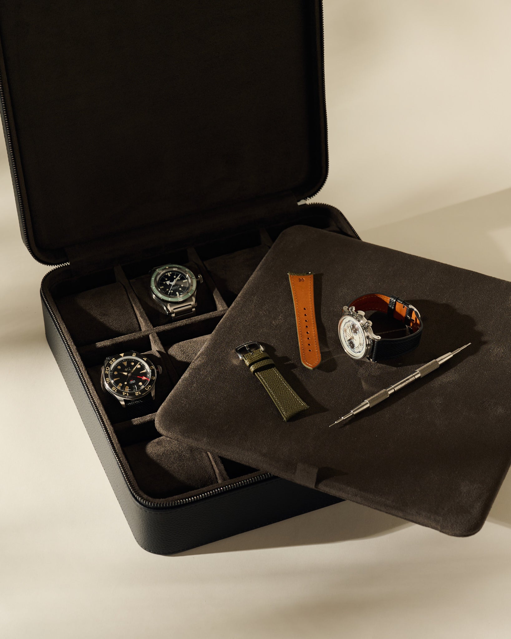 Open TAWBURY Fraser 12 Watch Case - Midnight Black with slots containing two watches, two spare watch straps, and a spring bar tool for organized watch storage.