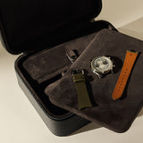 An open TAWBURY Fraser 3 Watch Case with Storage - Midnight Black containing a watch face, a green watch strap, and a brown watch strap resting on a dark fabric divider.