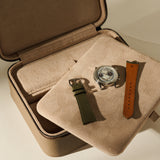 An open Fraser 3 Watch Case with Storage - Truffle Taupe featuring a cushioned tray holding a wristwatch and two separate watch straps.