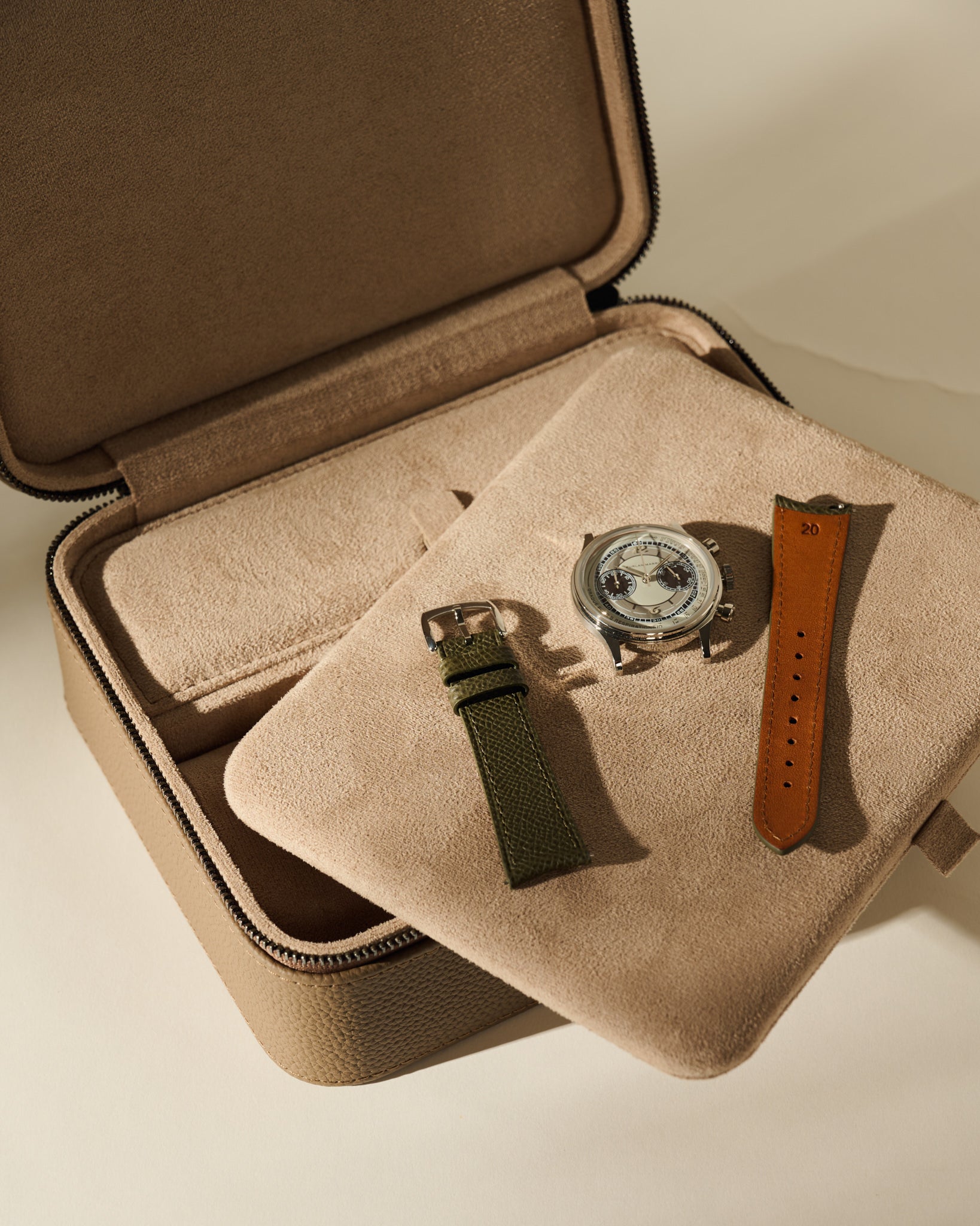 An open Fraser 3 Watch Case with Storage - Truffle Taupe featuring a cushioned tray holding a wristwatch and two separate watch straps.