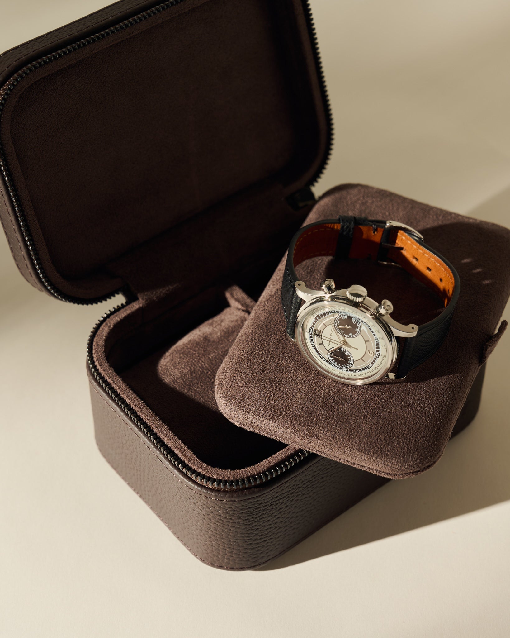 An open TAWBURY Fraser 2 Watch Case - Espresso Brown with a cushioned insert holding a silver chronograph wristwatch with a black leather strap.