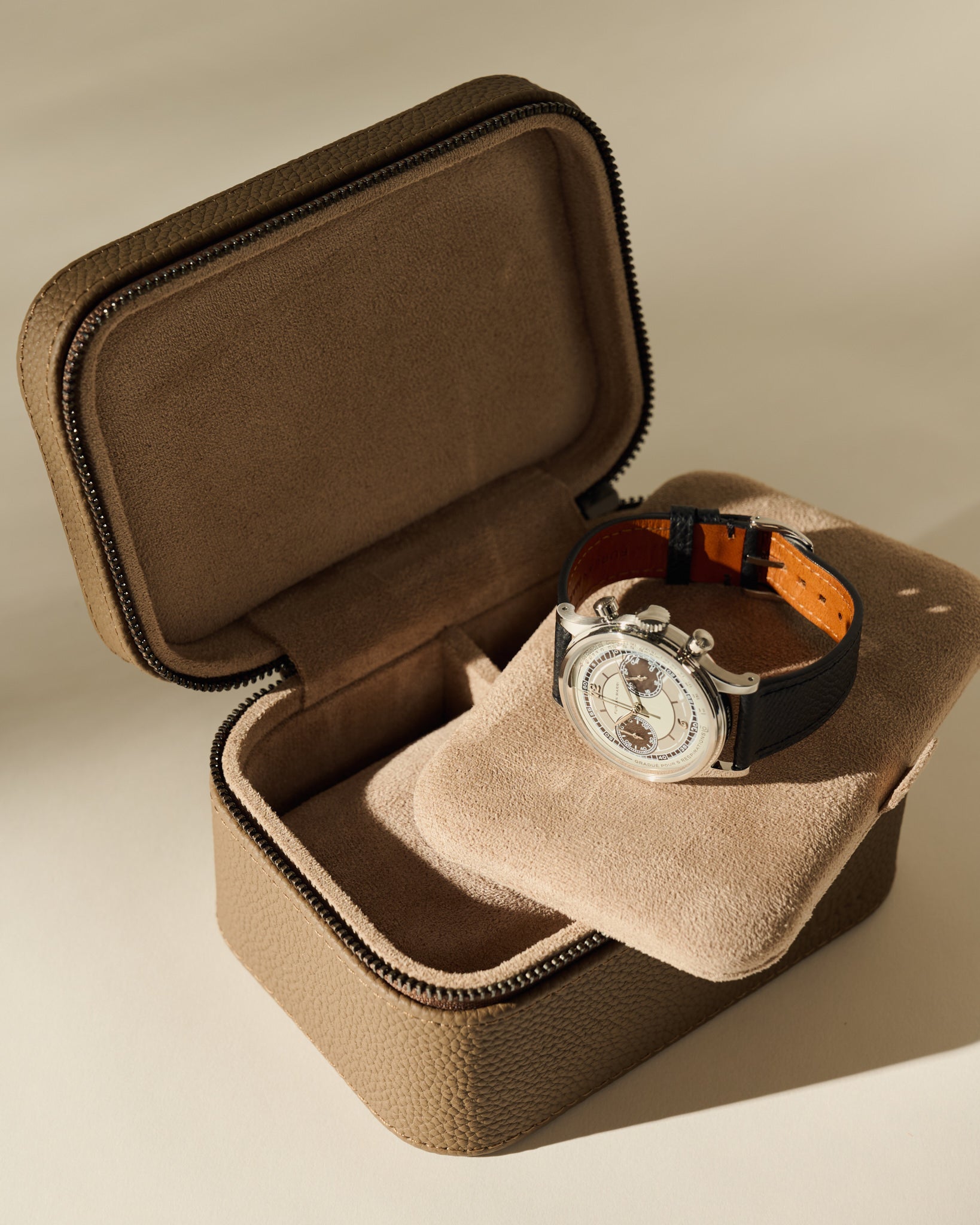 Open TAWBURY Fraser 2 Watch Case - Truffle Taupe with a cream-colored interior, displaying a silver chronograph wristwatch with a black leather strap.