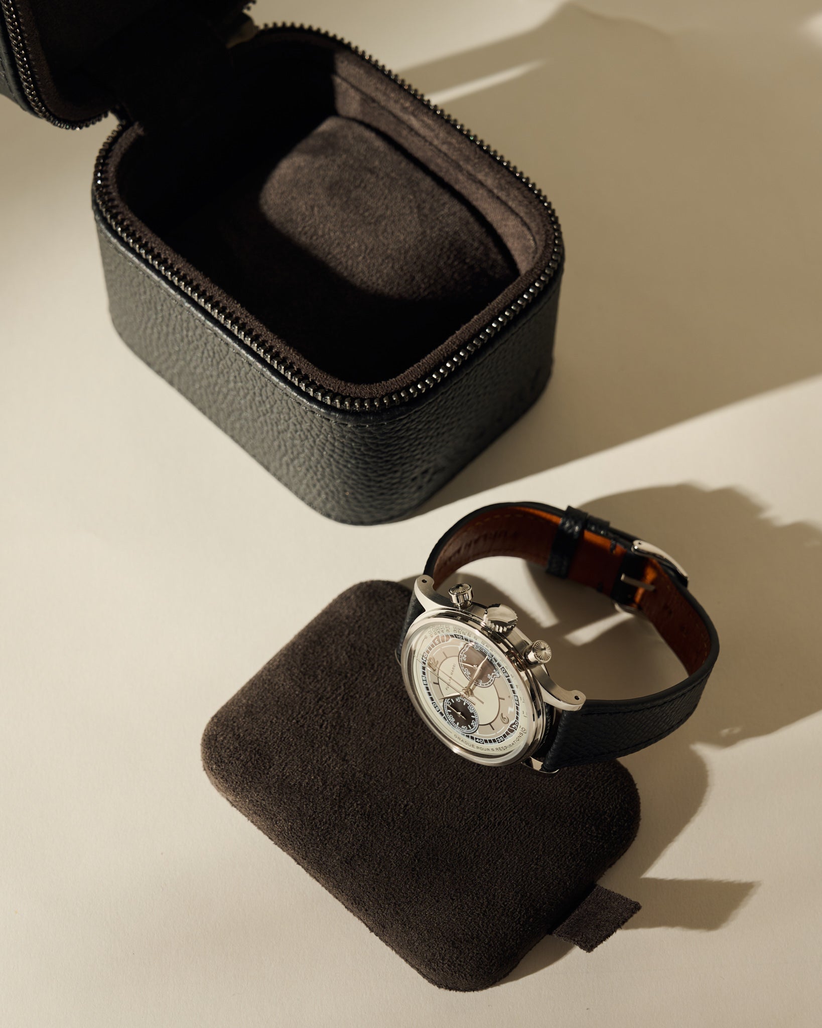An open black leather TAWBURY Fraser 1 Watch Case - Midnight Black sits next to a wristwatch resting on a removable interior cushion.