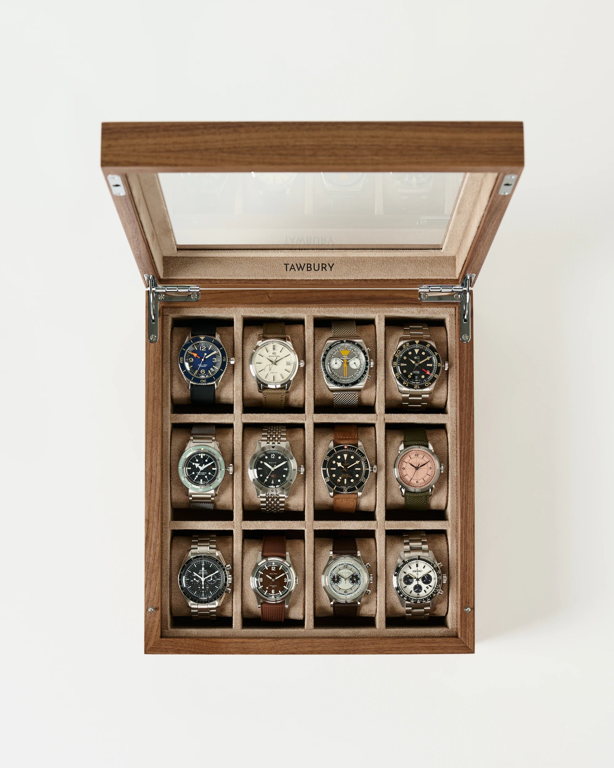 The TAWBURY Grove 12 Slot Wooden Watch Box in light walnut features a glass lid and twelve compartments, each holding a wristwatch, neatly arranged in three rows of four.