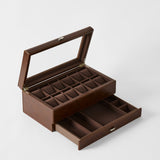 The TAWBURY Bayswater 12 Slot Watch Box in Chestnut Brown features a glass lid, multiple compartments for organized watch storage, and an open lower drawer with extra sections.