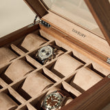 The TAWBURY Grove 12 Slot Wooden Watch Box in light walnut wood features a glass lid and beige suede compartments for stylish watch storage, displaying two wristwatches with ten slots ready for the rest of your collection.