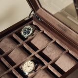 The TAWBURY Grove 12 Slot Wooden Watch Box in dark walnut wood features a glass lid, individual compartments, and brown suede lining—perfect for collectors to stylishly display and protect their wristwatches.