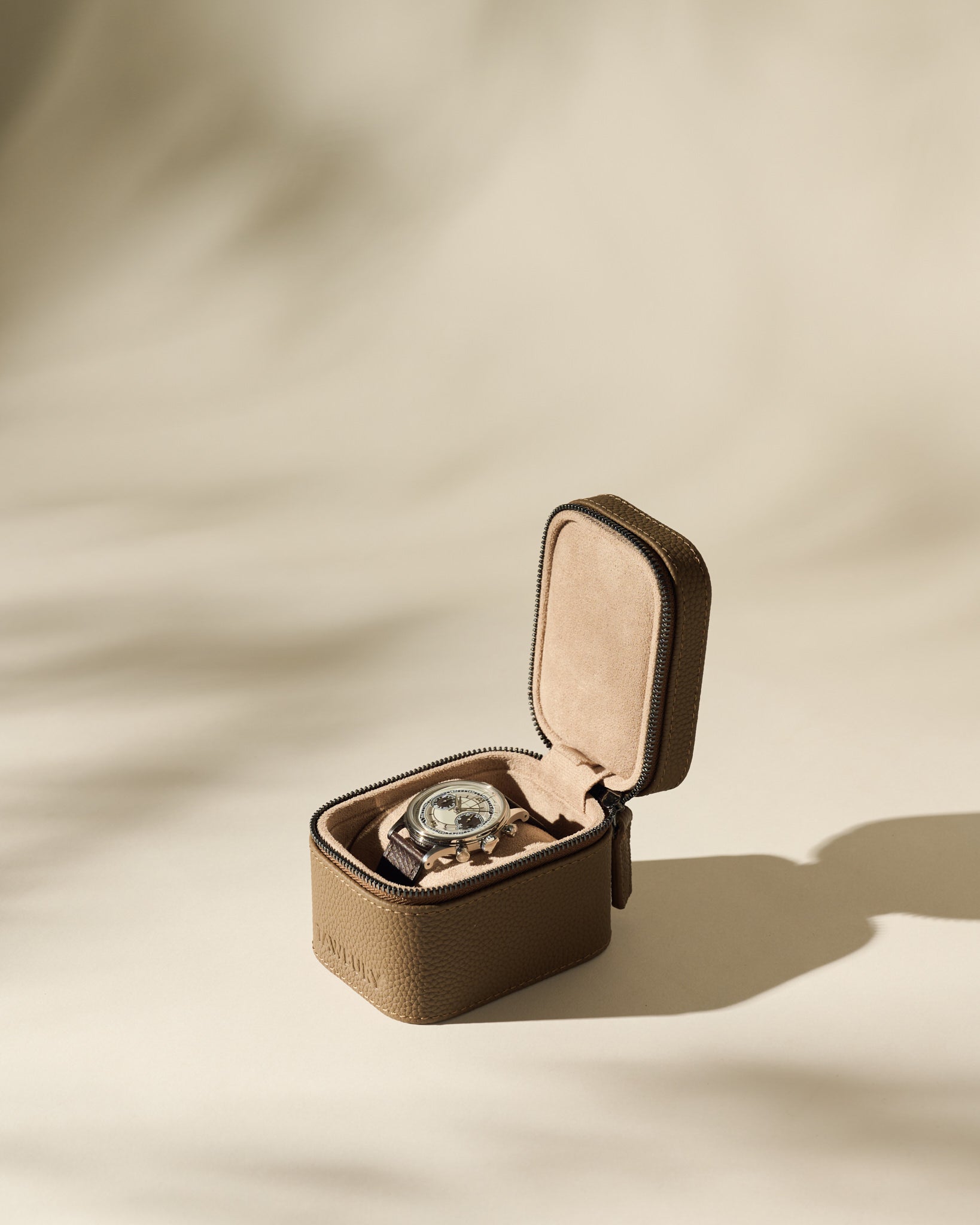 A wristwatch with a brown strap is displayed in an open TAWBURY Fraser 1 Watch Case - Taupe on a neutral background.