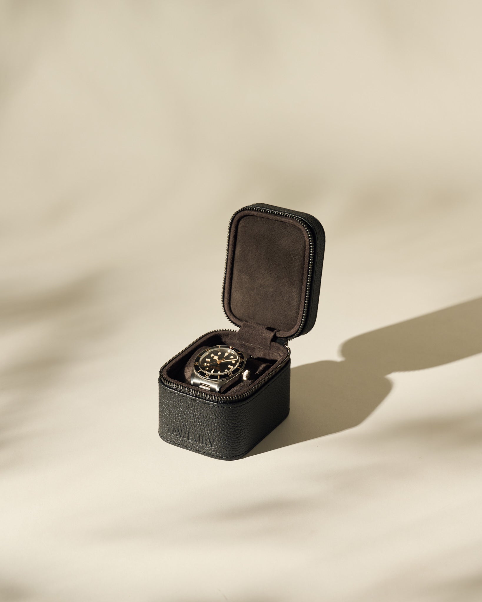 The TAWBURY Fraser 1 Watch Case in black is shown open on a neutral background, featuring soft lighting and subtle shadows.