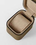 The TAWBURY Fraser 1 Watch Case in taupe features a textured fabric exterior, soft cushioned interior, and secure zipper closure. Shown open and empty.