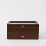 The TAWBURY Bayswater 24 Slot Watch Box with Drawer in chestnut brown features a glass top, metal handles, and "TAWBURY" embossed on the front—ideal for watch storage. Shown against a plain white background.